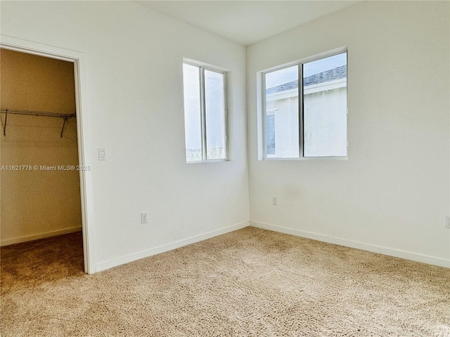 unfurnished bedroom with a spacious closet, carpet floors, and a closet