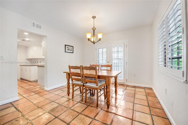 tiled dining room featuring french doors and a notable chandelier