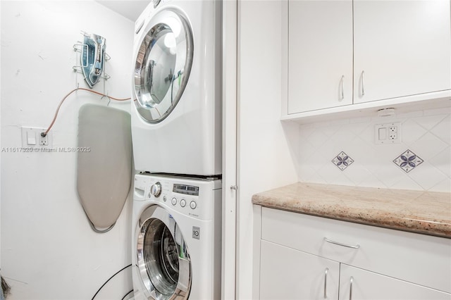 washroom with cabinets and stacked washer / dryer