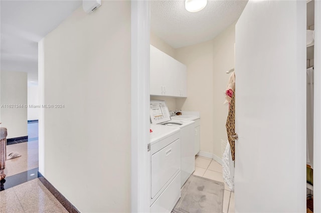 clothes washing area with washer and dryer, cabinets, and a textured ceiling