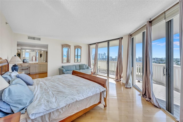 bedroom featuring multiple windows, floor to ceiling windows, light hardwood / wood-style floors, and access to exterior