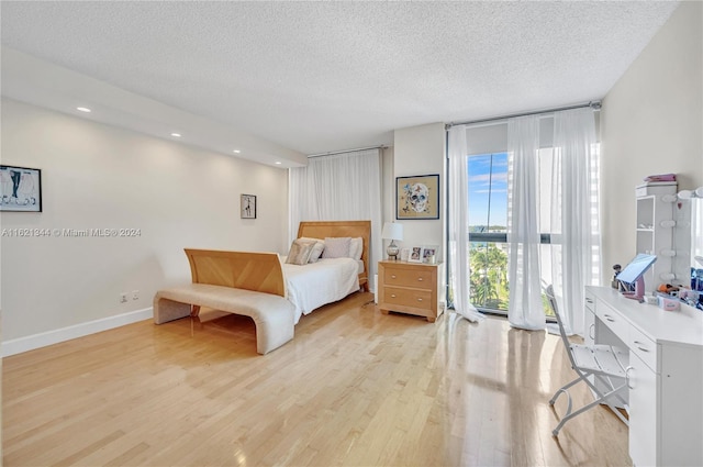 bedroom featuring a textured ceiling, light hardwood / wood-style flooring, and floor to ceiling windows