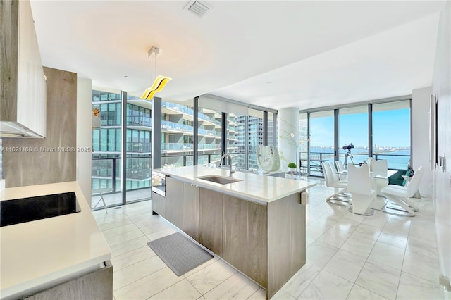 kitchen featuring pendant lighting, sink, floor to ceiling windows, a water view, and black electric cooktop