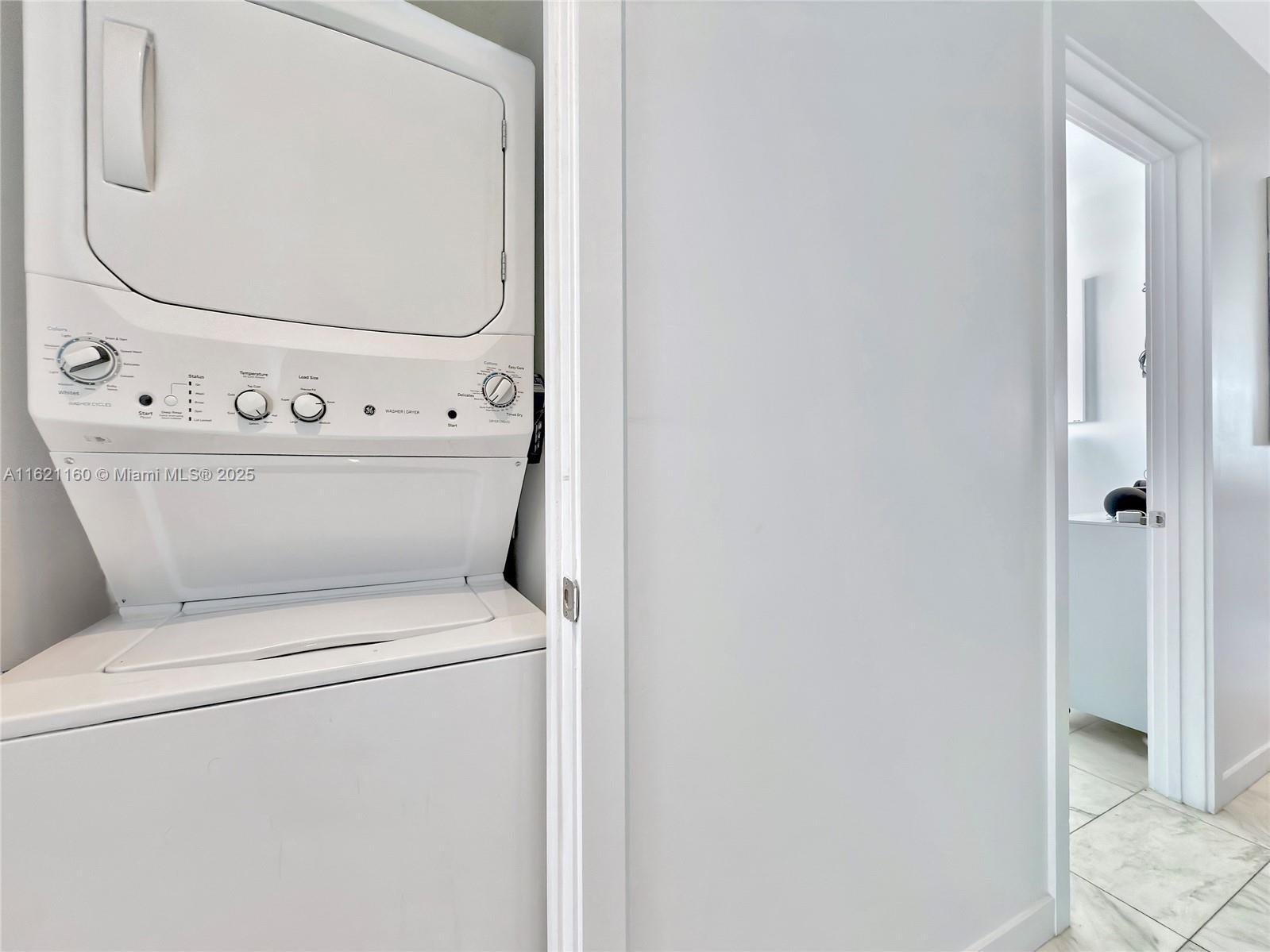 laundry area with stacked washer and dryer and light tile patterned floors