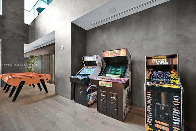 recreation room featuring a high ceiling and light wood-type flooring