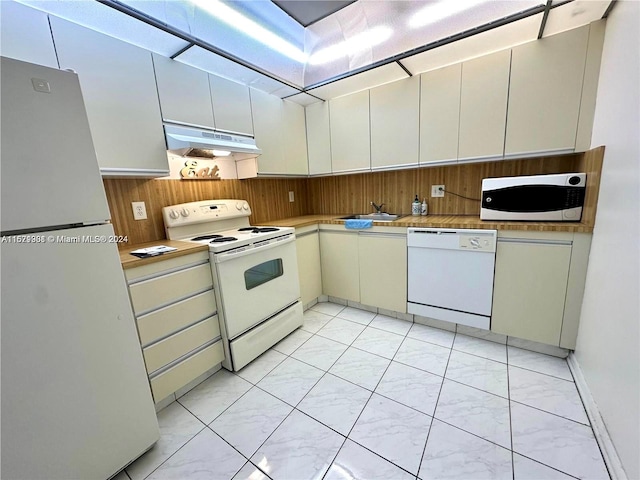 kitchen featuring sink, custom range hood, white appliances, and light tile patterned floors