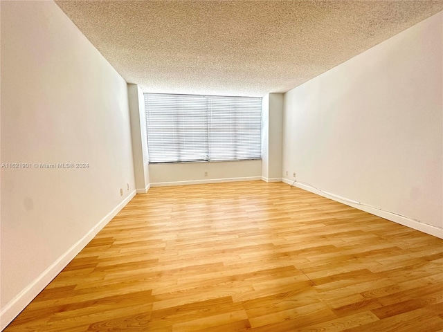 spare room featuring light hardwood / wood-style floors and a textured ceiling