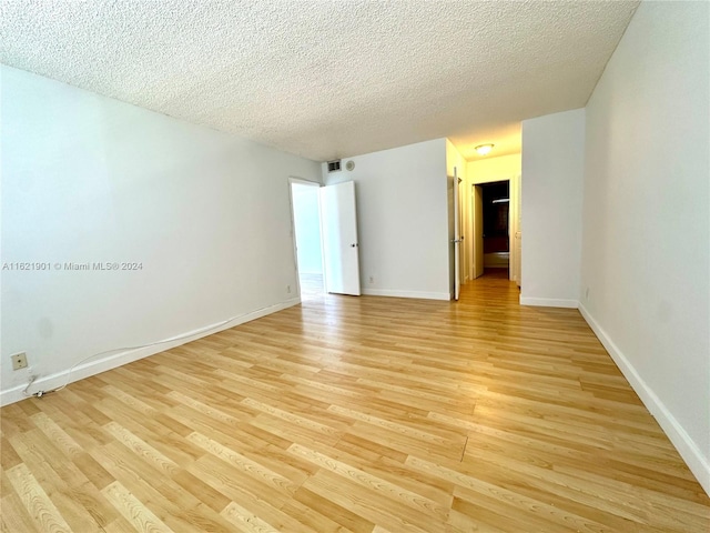 unfurnished room featuring light hardwood / wood-style floors and a textured ceiling