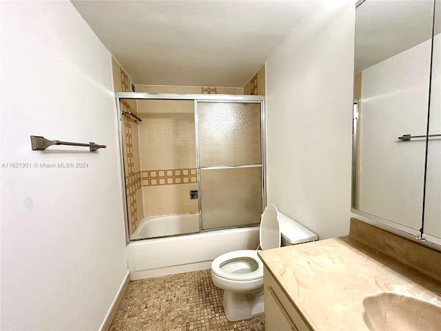 full bathroom featuring tile patterned floors, combined bath / shower with glass door, vanity, and toilet