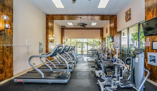 gym featuring a drop ceiling, ceiling fan, and a high ceiling