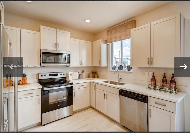 kitchen featuring light tile patterned floors, white cabinetry, appliances with stainless steel finishes, and sink