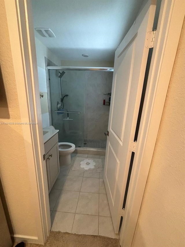 bathroom featuring vanity, toilet, tile patterned flooring, and walk in shower