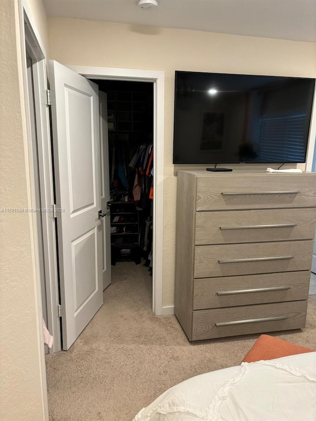 bedroom featuring a closet, light colored carpet, and a spacious closet