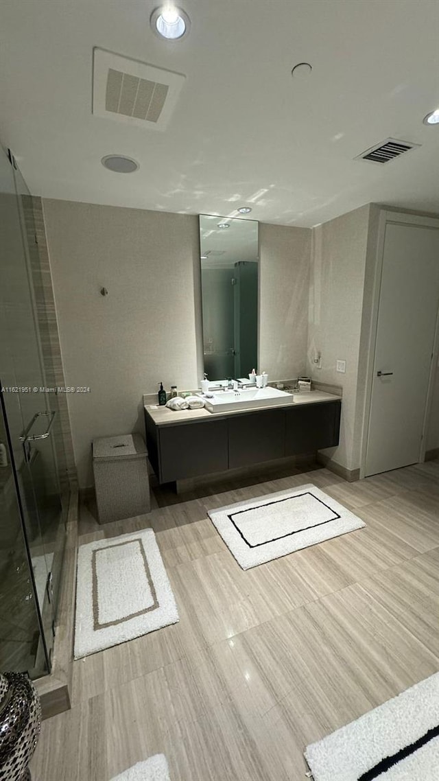 bathroom featuring a shower with shower door and vanity