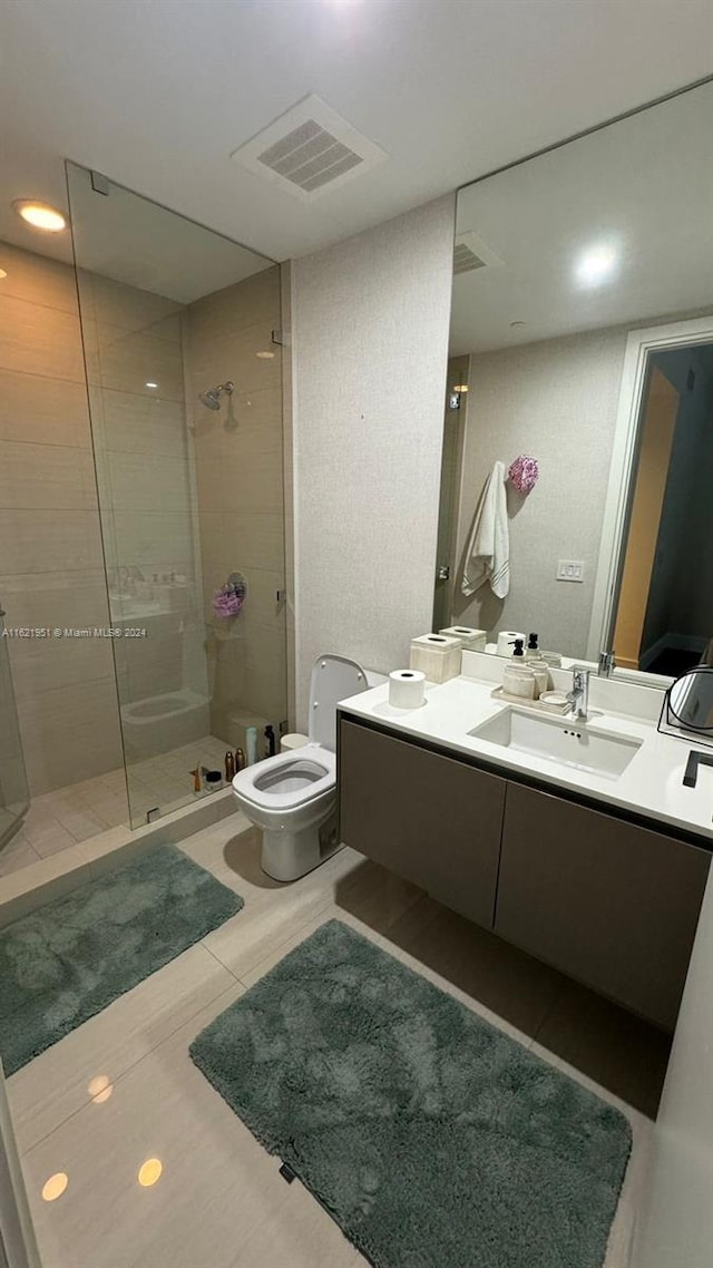 bathroom featuring tile patterned flooring, toilet, vanity, and an enclosed shower