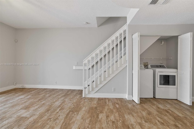 interior space featuring light hardwood / wood-style flooring, washer and clothes dryer, and a textured ceiling