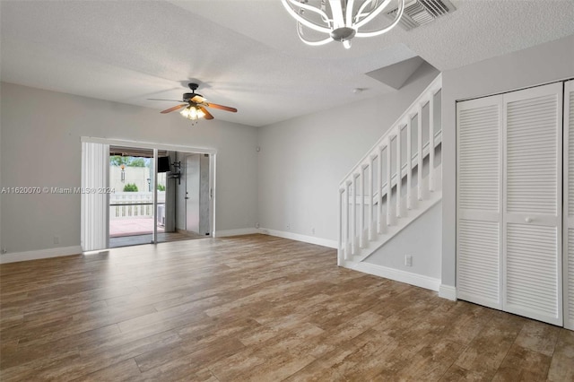 unfurnished room featuring ceiling fan with notable chandelier, hardwood / wood-style floors, and a textured ceiling