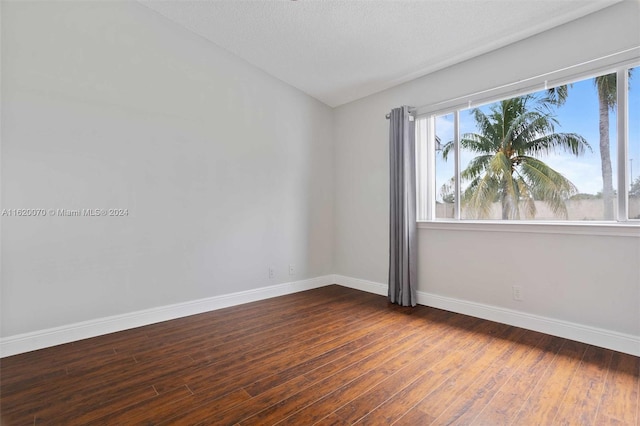 empty room with a textured ceiling and dark wood-type flooring