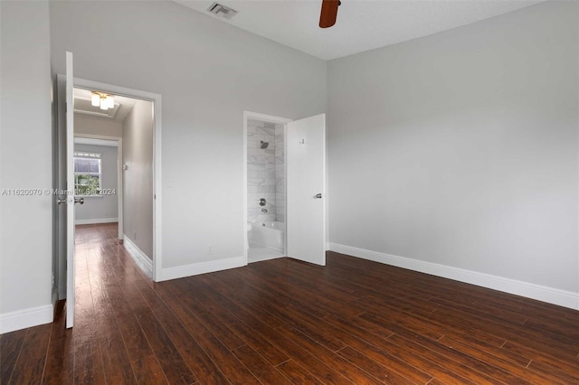 unfurnished bedroom featuring ensuite bathroom, a high ceiling, dark hardwood / wood-style floors, and ceiling fan