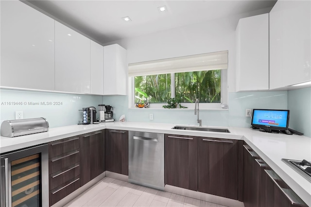 kitchen with dark brown cabinetry, sink, white cabinetry, dishwasher, and beverage cooler