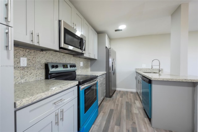 kitchen with white cabinetry, sink, light stone counters, and stainless steel appliances