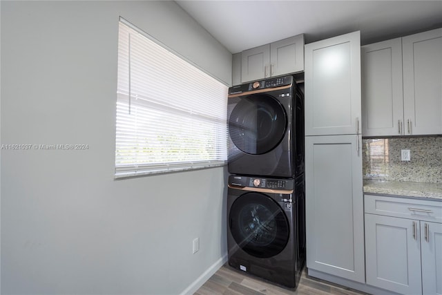 laundry room with cabinets, stacked washer / dryer, and light hardwood / wood-style flooring