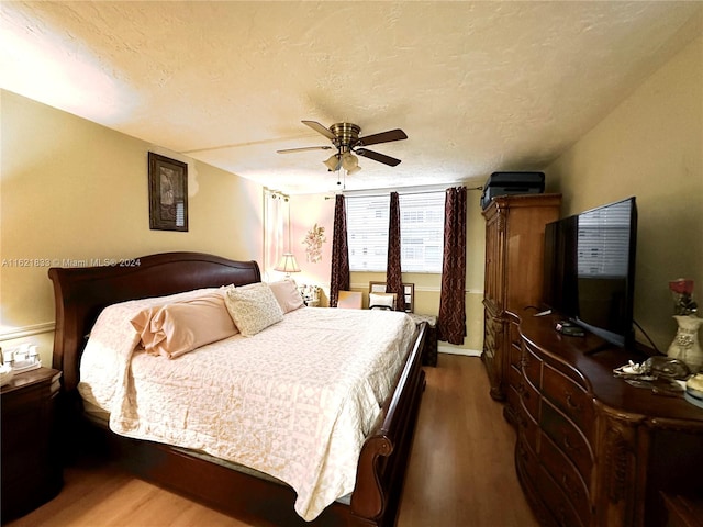 bedroom featuring dark hardwood / wood-style floors, ceiling fan, and a textured ceiling