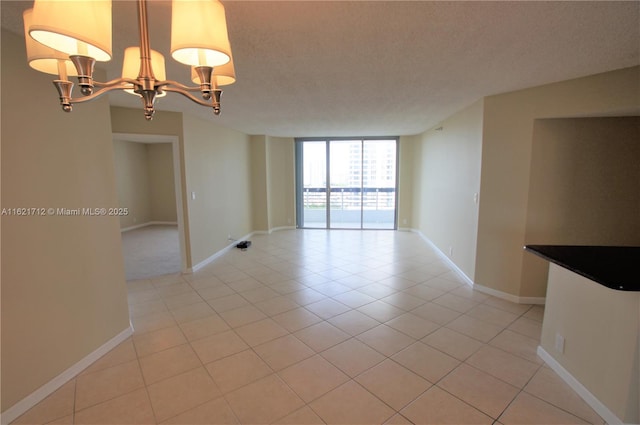 unfurnished room featuring light tile patterned floors, a textured ceiling, an inviting chandelier, and expansive windows