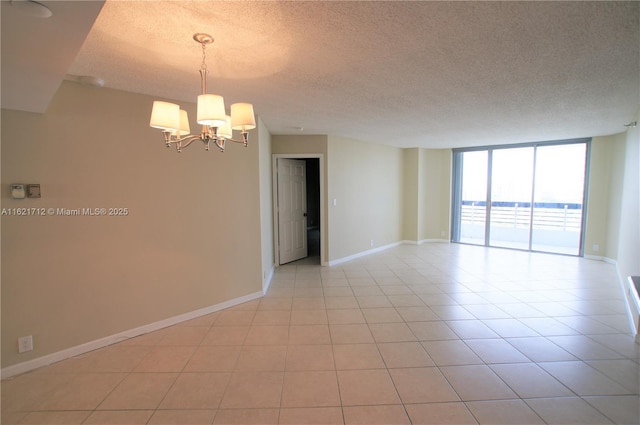 empty room featuring floor to ceiling windows, light tile patterned floors, a chandelier, and a textured ceiling