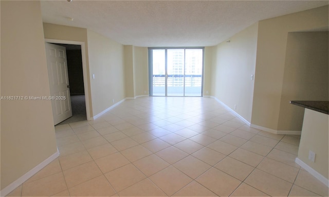 unfurnished room featuring a textured ceiling, a wall of windows, and light tile patterned flooring