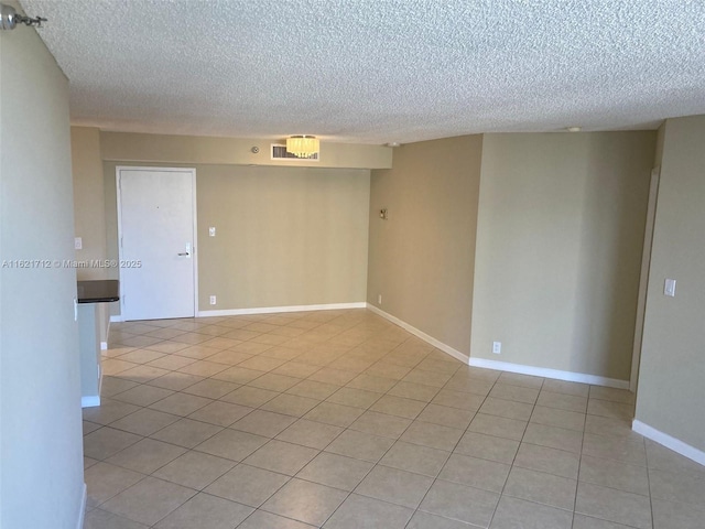 tiled empty room featuring a textured ceiling