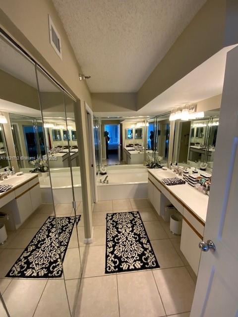 bathroom with tile patterned floors, a bath, and a textured ceiling