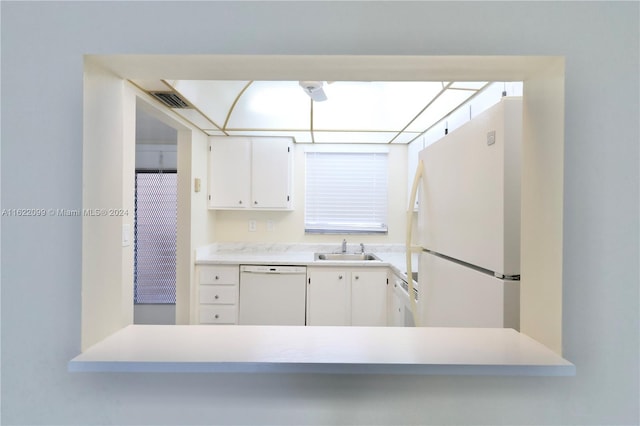 kitchen with white appliances, kitchen peninsula, sink, and white cabinets