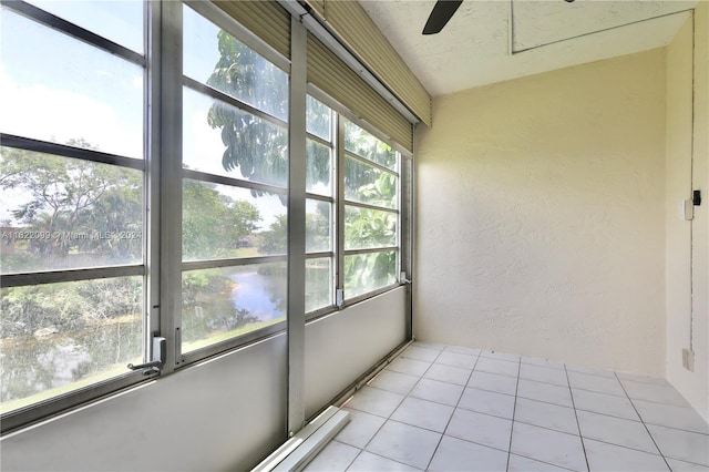 unfurnished sunroom with ceiling fan and a water view