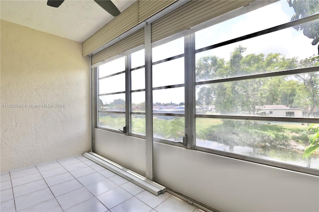 unfurnished sunroom featuring ceiling fan and a water view