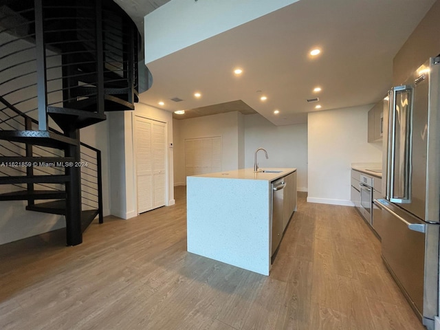 kitchen featuring stainless steel appliances, hardwood / wood-style floors, sink, and an island with sink