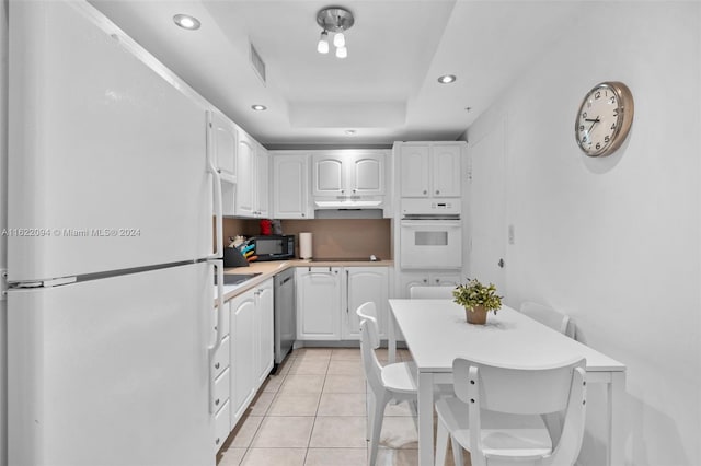 kitchen with a raised ceiling, white cabinetry, white appliances, and light tile patterned floors