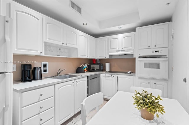 kitchen with white cabinets, white appliances, sink, and a tray ceiling