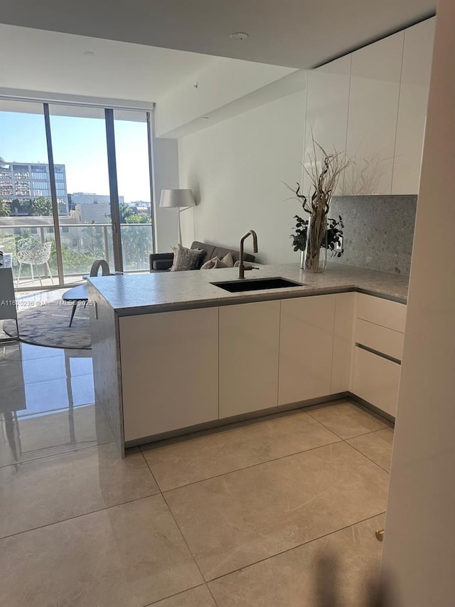 2678 Tigertail Ave Unit 515, Miami, FL 33133 - kitchen featuring a sink, white cabinetry, a peninsula, and light tile patterned floors