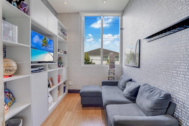 living room with light wood-type flooring and brick wall