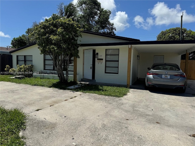 view of front of house with stucco siding, a carport, and concrete driveway