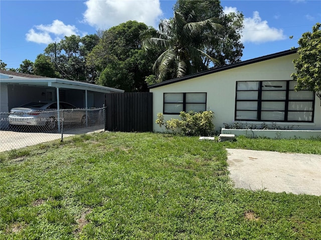 view of yard with a carport, driveway, and fence