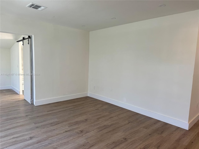 unfurnished room with hardwood / wood-style floors and a barn door