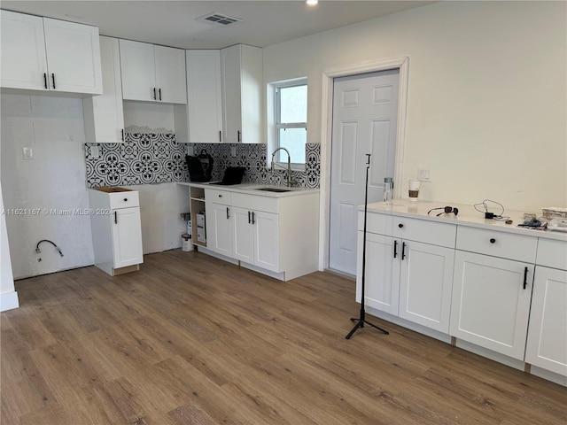 kitchen featuring white cabinets, hardwood / wood-style flooring, and backsplash