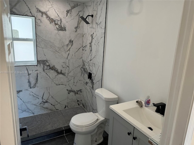 bathroom with tile patterned floors, vanity, tiled shower, and toilet