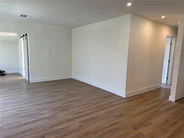 unfurnished room with a barn door and dark wood-type flooring