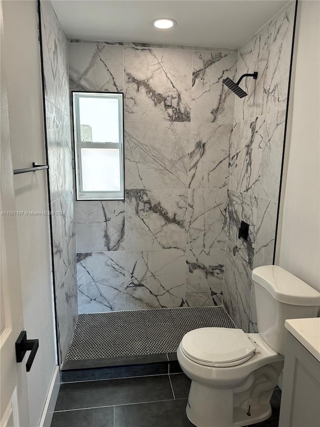 bathroom featuring vanity, tile patterned flooring, a tile shower, and toilet