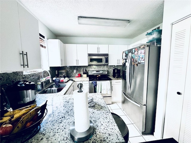 kitchen with a textured ceiling, white cabinetry, sink, and stainless steel appliances