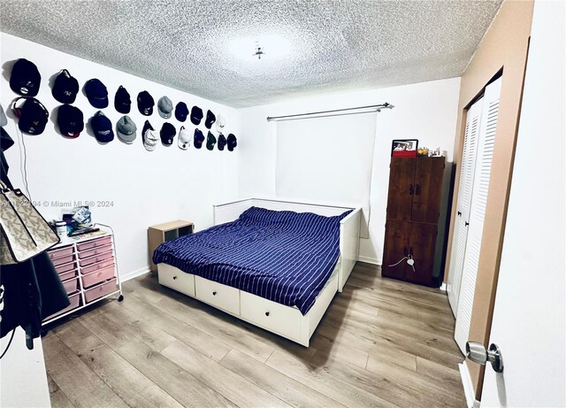 bedroom featuring a textured ceiling, light hardwood / wood-style flooring, and a closet