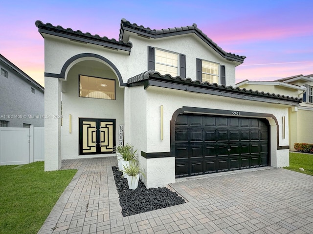 mediterranean / spanish-style home featuring a garage and a lawn